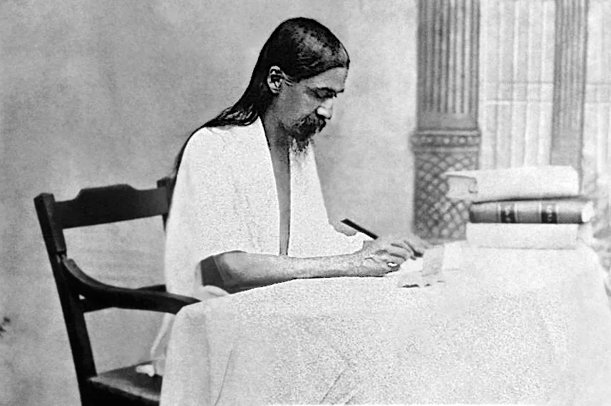 Sri Aurobindo (1872-1950) writes at a table.